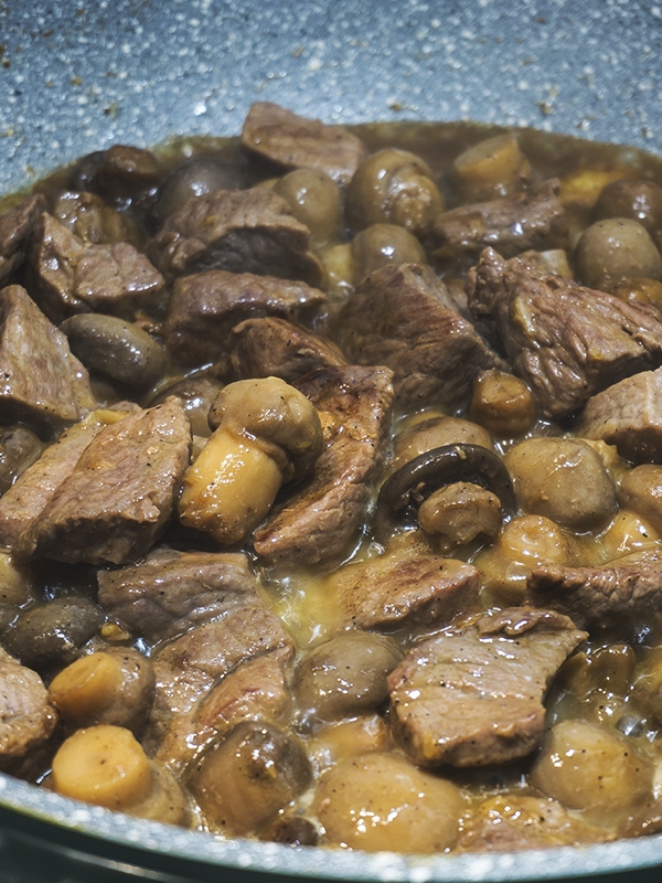 beef and mushrooms cooking in a pan