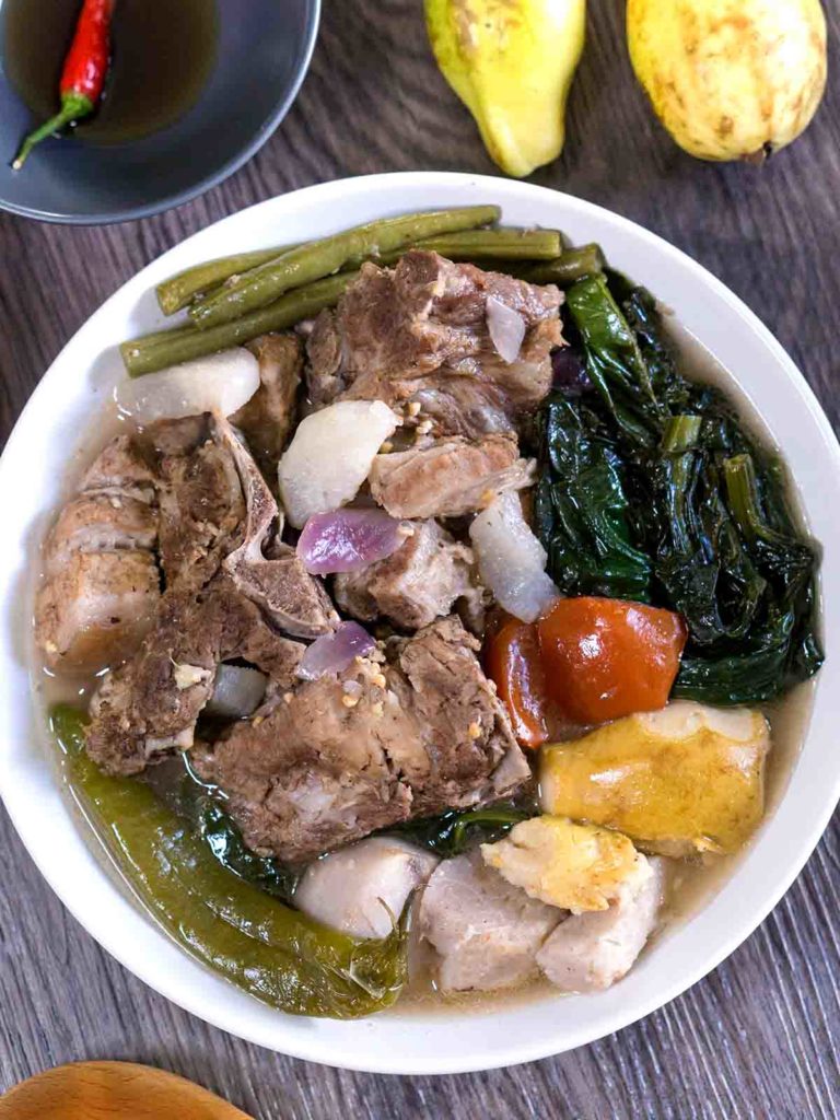 pork stew with vegetables in a bowl on top of table with dipping sauce