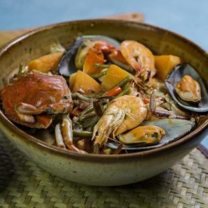 shellfish mix with vegetables with coconut milk in a bowl on top of table