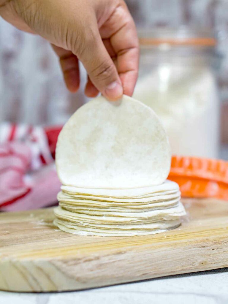 dumpling wraps stacked on top of a board on top of table