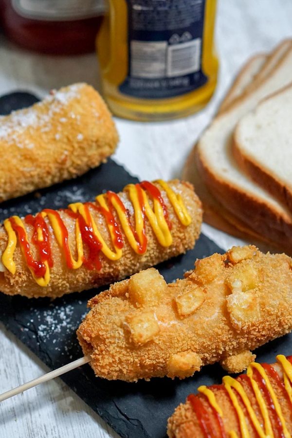 bread with hotdog in a plate on top of table with ketchup and mustard