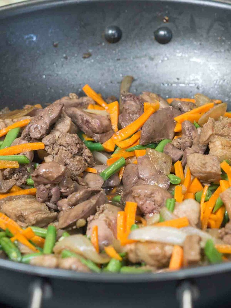 meat and vegetables frying in a wok