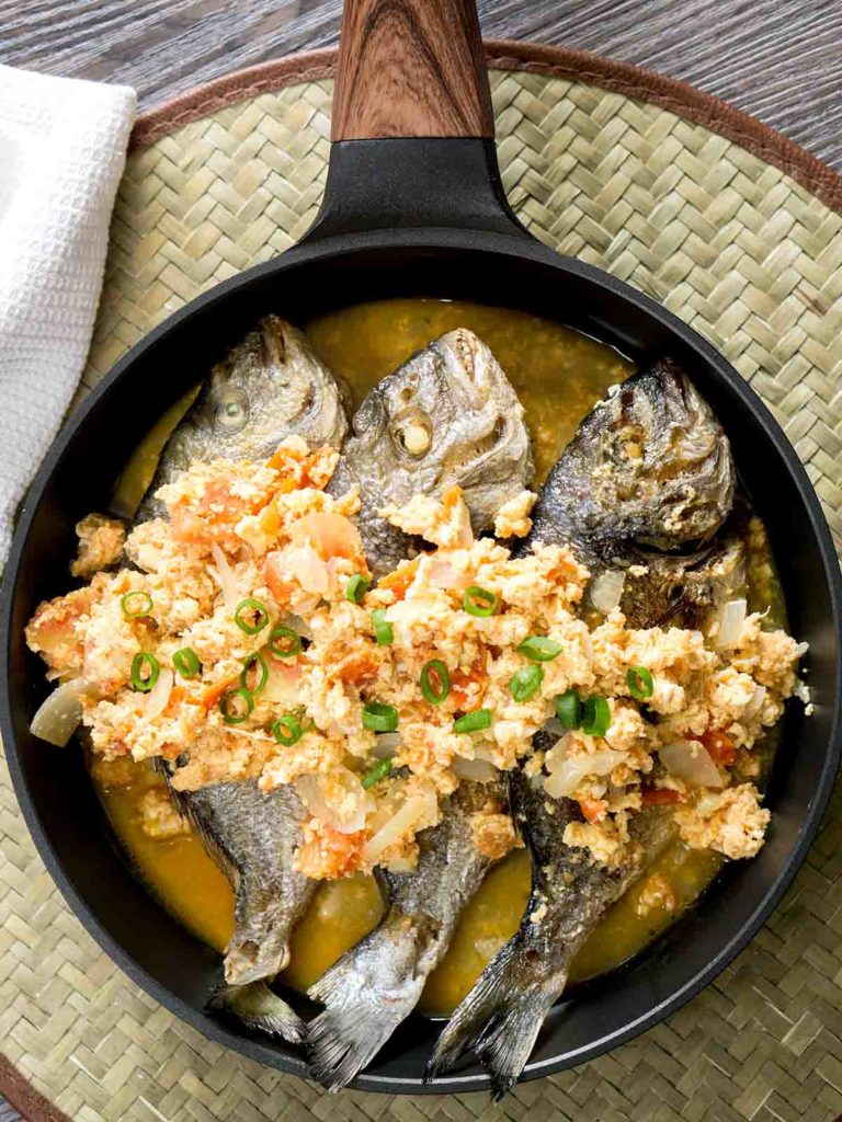 fish with sauce in a pan on top of table