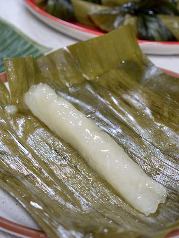 unwrapped rice cake on top of banana leaf in a plate